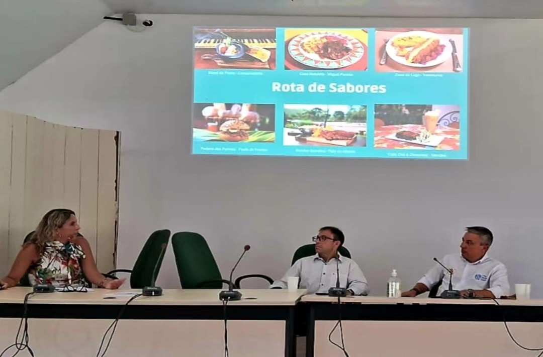 três participantes do evento sendo uma mulher e dois homens sentados debatendo sobre o tema apresentado no evento