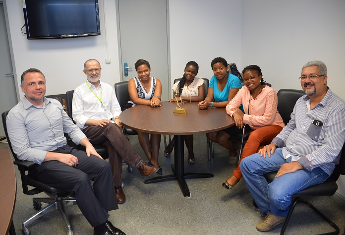Reitor, profissionais do IFRJ e professoras moçambicanas posam para a foto sentados ao redor de uma mesa