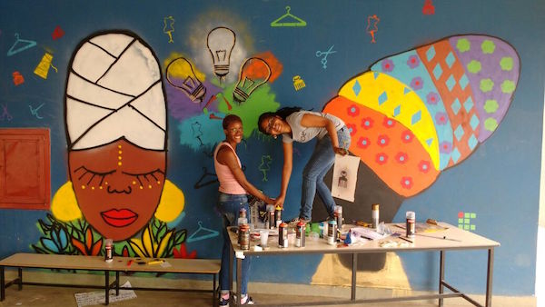 Duas artistas grafitando uma parede em comemoraçãoao dia da consciência negra