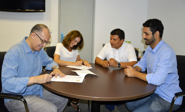 Reitor e assessora internacional do IFRJ assinam termo de parceria. Juntos, sentados ao redor da mesa, encontram-se também o representante do Peru e diretor de implantação do campus Belford Roxo.